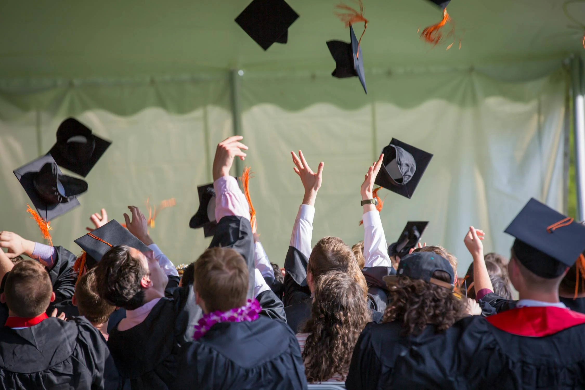 Group of college graduates throwing their caps into the air.